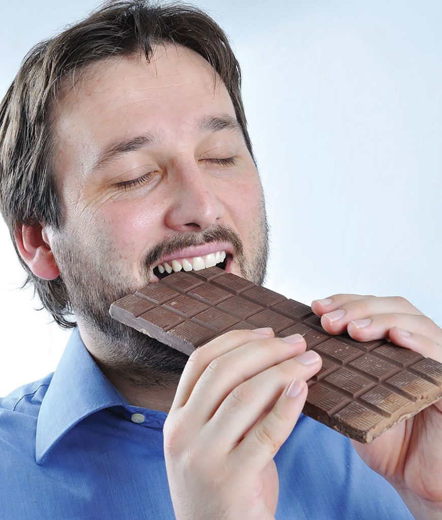 Мужчина ест шоколад