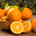 Close up of some oranges in a basket over a wooden surface