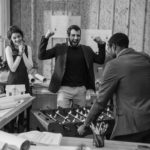 young architects playing table football at modern office