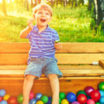 Happy child playing with colorful plastic balls