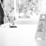 Safety sign with phrase Caution wet floor and blurred cleaner on