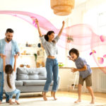 Happy parents with kids dancing in modern living room