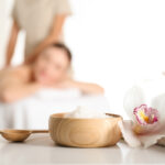Bowl with sea salt and orchid flower on white table in spa salon