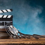Cinema concept of vintage film reel with popcorn on old wooden background.