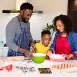 Happy african american parent and son baking together in kitchen. family time, having fun together at home.