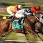 Slow shutter speed rendering of several racing horses and jockeys.