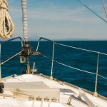 A sea voyage on a sunny, warm day. The bow of a yacht ship, ship’s ropes. Yachting, nautical tourism. Marine landscape. The hills against blue sky and blue sea ocean water. Summer holidays trip.