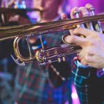 Concert view of a male trumpeter, professional trumpet player with vocalist and musical during jazz band performing